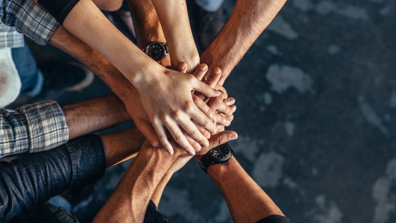 Multiple people putting their hands together in a show of solidarity or teamwork.